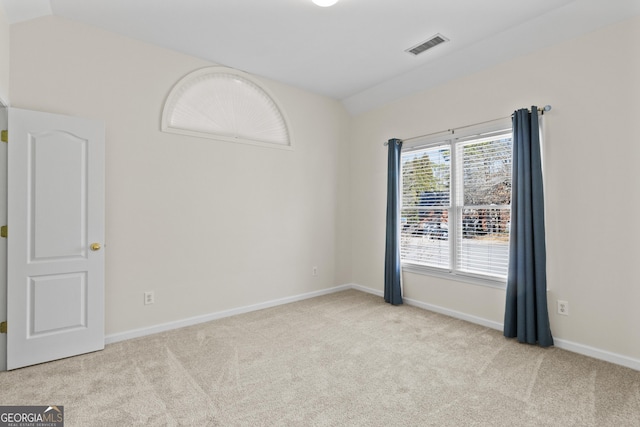 carpeted spare room featuring lofted ceiling, visible vents, and baseboards