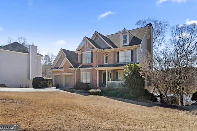 craftsman house with covered porch, brick siding, a chimney, and an attached garage