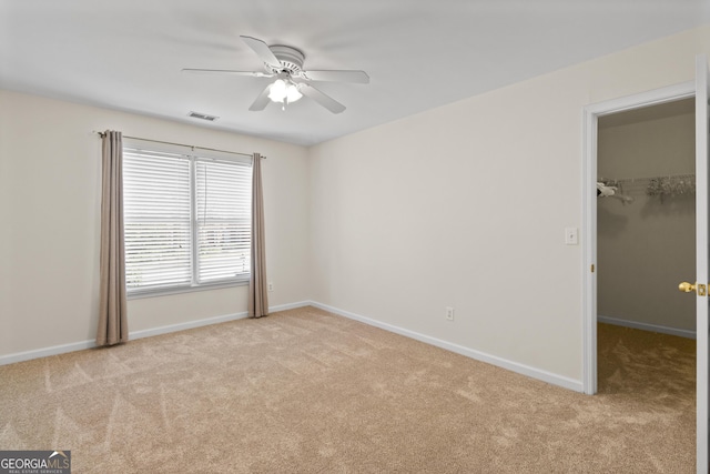 unfurnished bedroom with carpet, visible vents, a spacious closet, and baseboards