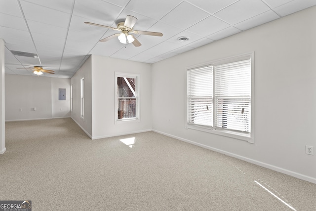 empty room with visible vents, a ceiling fan, carpet flooring, a drop ceiling, and baseboards