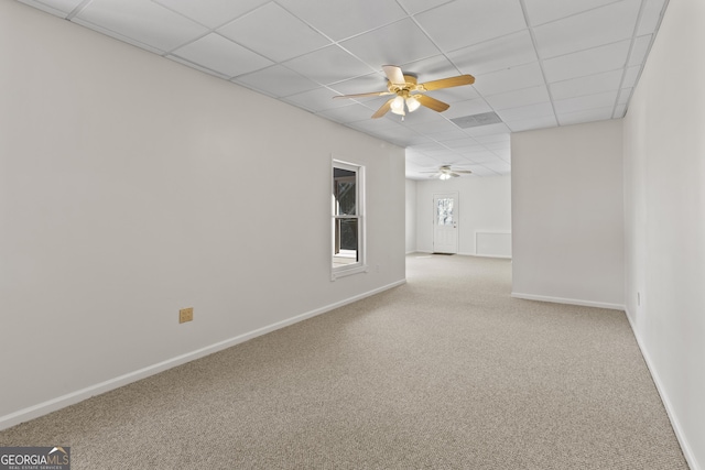 spare room with ceiling fan, a drop ceiling, carpet flooring, and baseboards