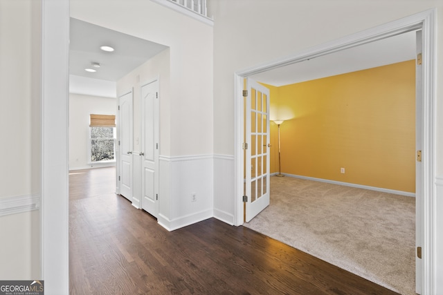 hallway featuring carpet, baseboards, and wood finished floors