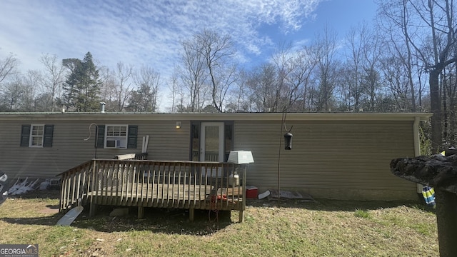 rear view of property featuring a lawn and a wooden deck