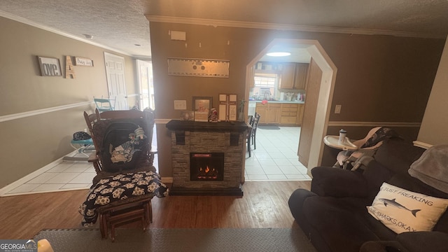 living room with a fireplace, ornamental molding, a textured ceiling, and wood finished floors