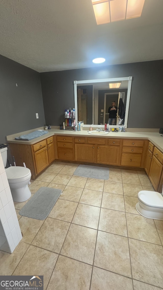 bathroom featuring tile patterned flooring, a sink, a textured ceiling, and toilet