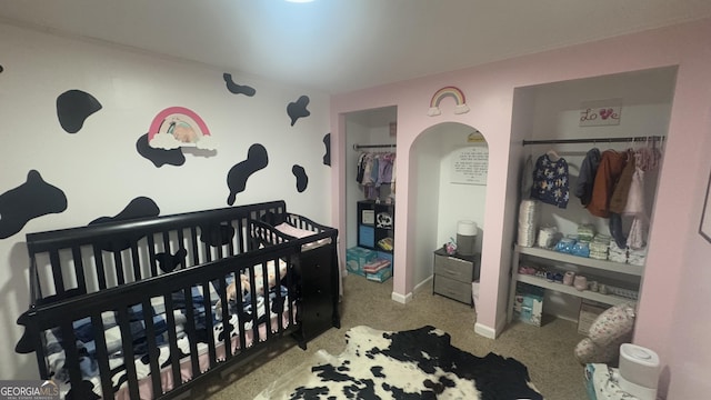 carpeted bedroom featuring arched walkways and a closet