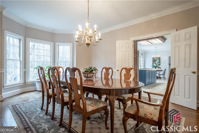 dining room featuring light wood finished floors, crown molding, and a notable chandelier