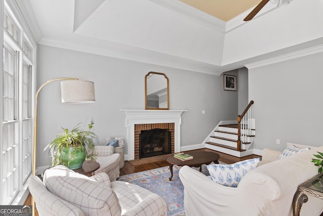 living area featuring ceiling fan, a fireplace, wood finished floors, baseboards, and ornamental molding