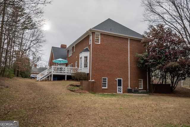 view of side of property featuring a yard, stairway, a deck, and brick siding