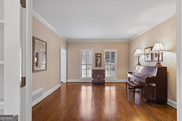 sitting room with ornamental molding, wood finished floors, visible vents, and baseboards