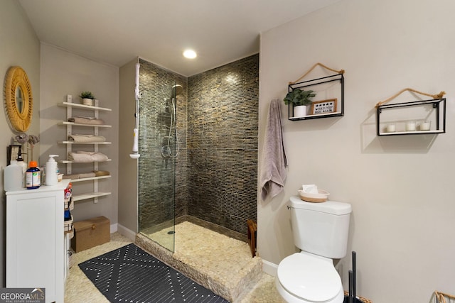 full bath featuring toilet, baseboards, and tiled shower