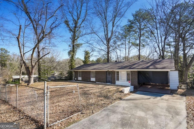 ranch-style house featuring driveway, fence, an attached carport, and brick siding