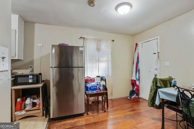 kitchen with light wood-style flooring, black microwave, and freestanding refrigerator