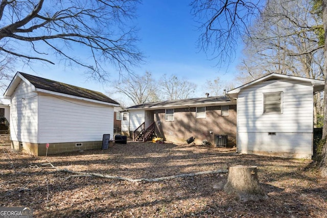 back of property with crawl space, brick siding, central AC unit, and an outbuilding