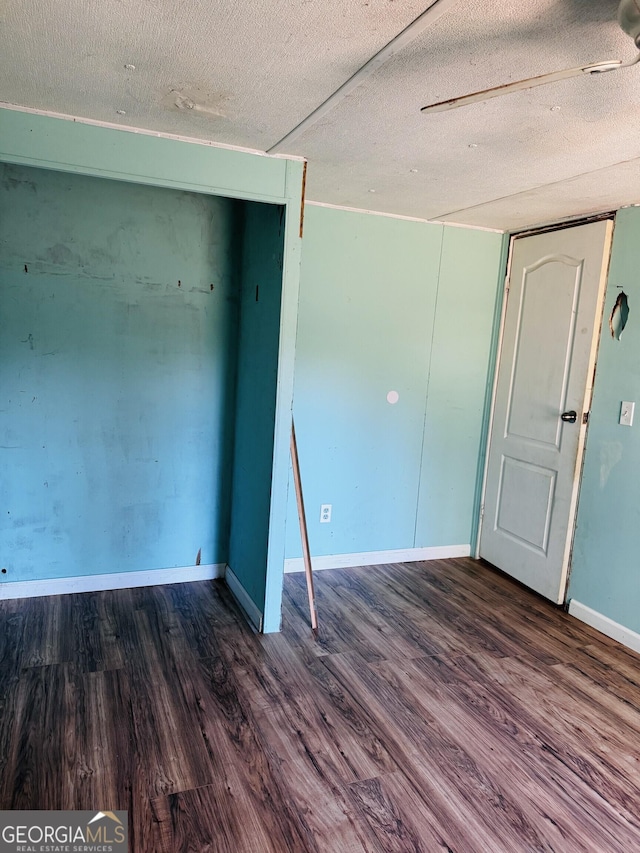 spare room with a textured ceiling, wood finished floors, and baseboards