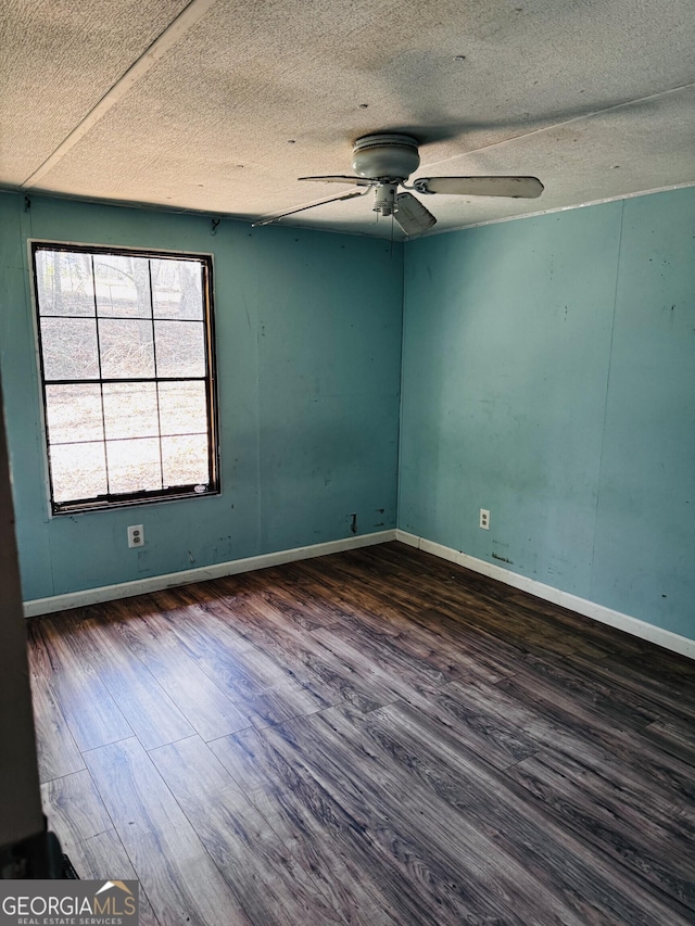 empty room featuring dark wood-style floors, a textured ceiling, baseboards, and a ceiling fan