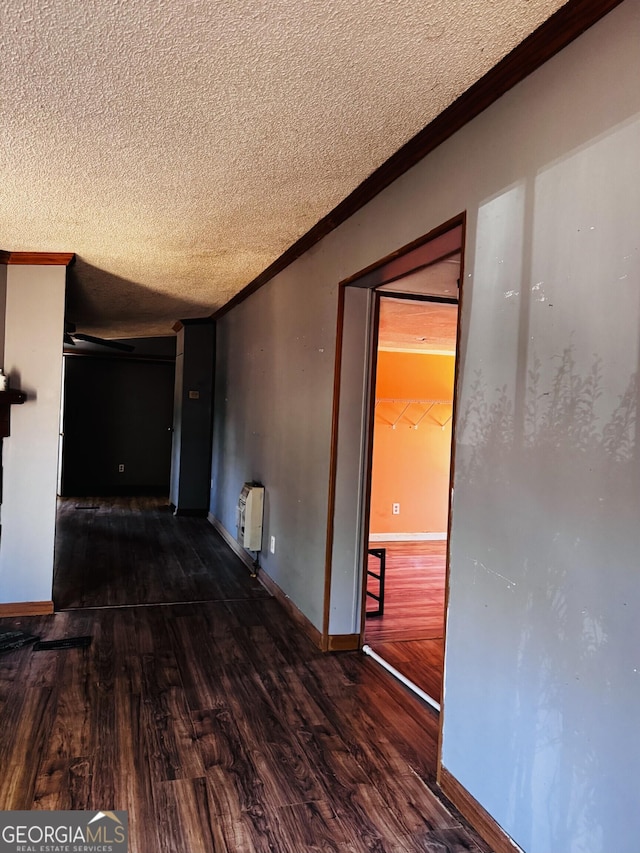 hallway featuring crown molding, a textured ceiling, baseboards, and wood finished floors