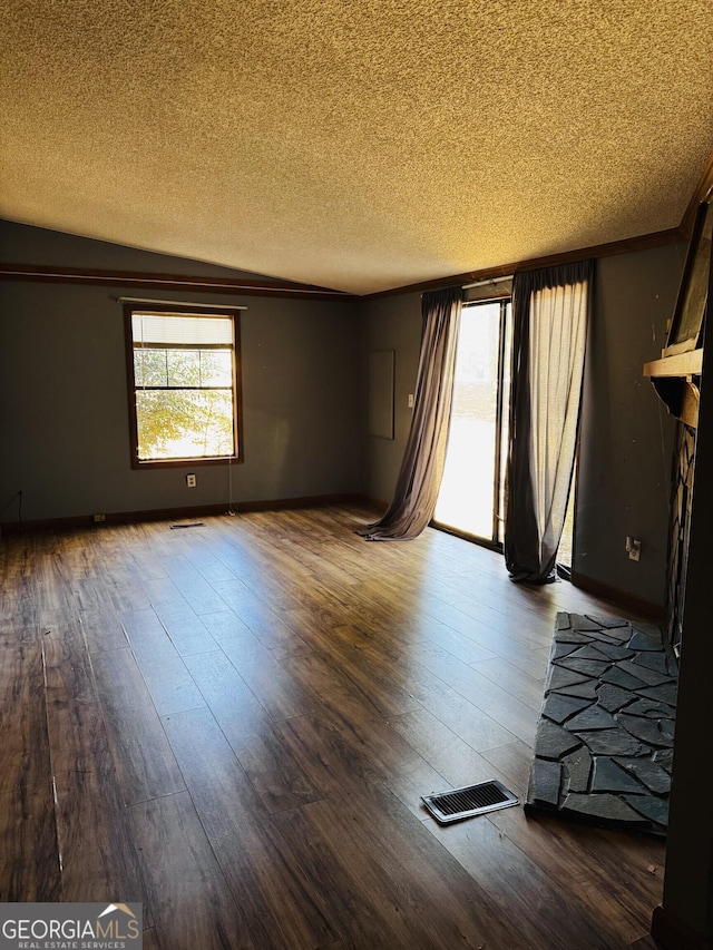 unfurnished living room with wood-type flooring, visible vents, ornamental molding, a textured ceiling, and baseboards