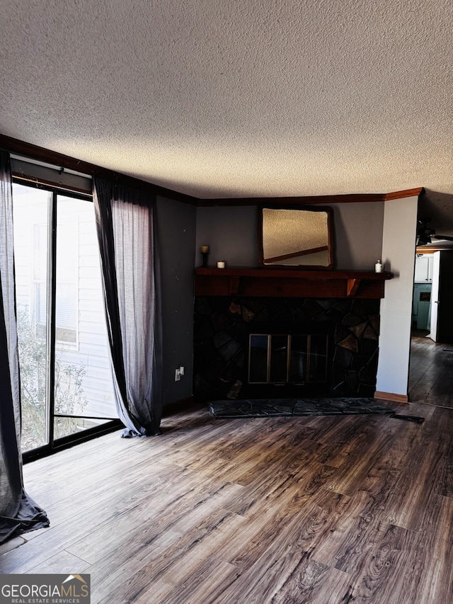 living area with a fireplace, a textured ceiling, and wood finished floors