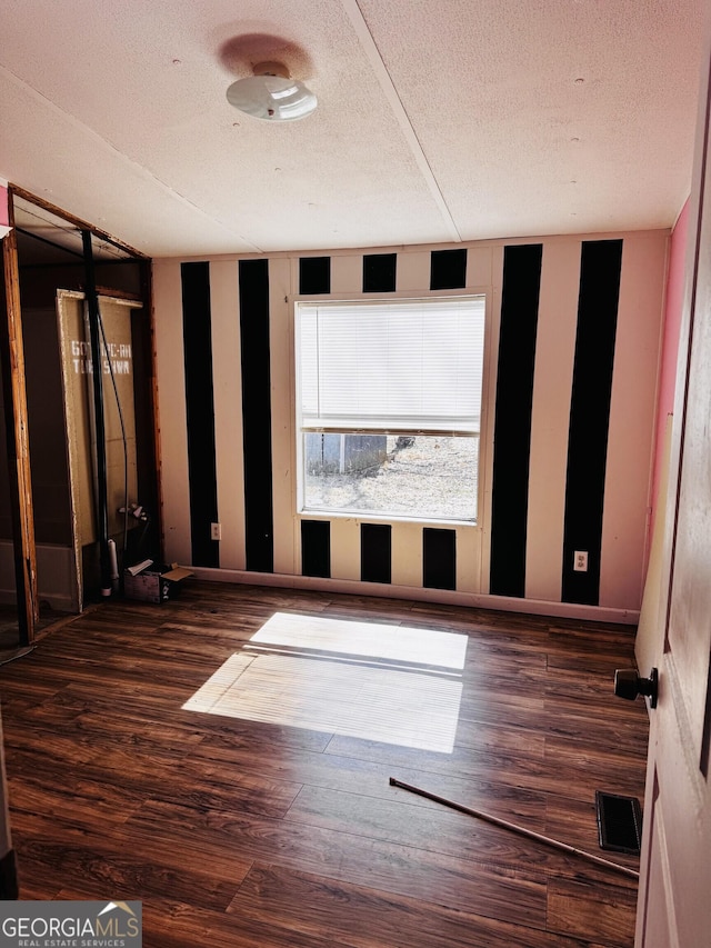 empty room with baseboards, a textured ceiling, visible vents, and wood finished floors