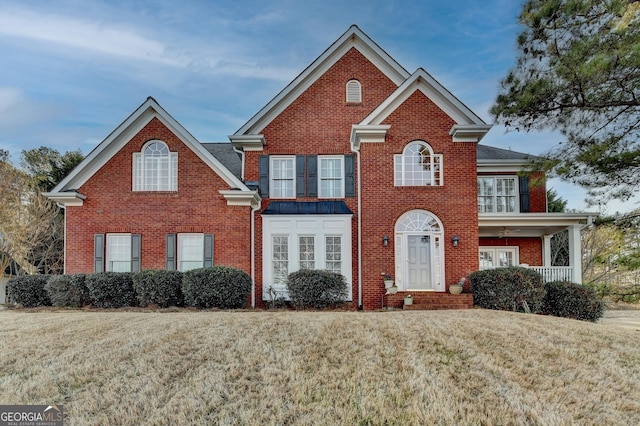 view of front facade featuring brick siding, a front lawn, and a balcony