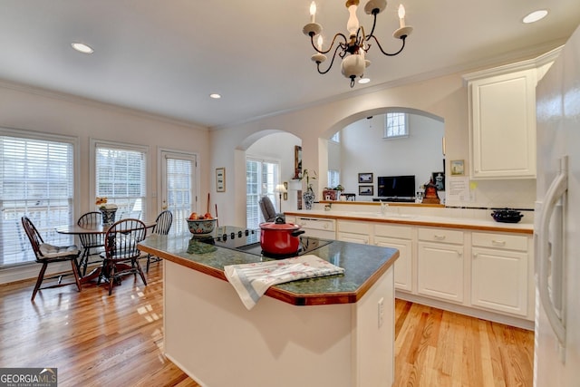 kitchen featuring a center island, white refrigerator with ice dispenser, crown molding, light wood finished floors, and backsplash