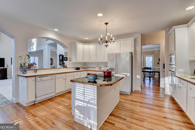 kitchen with white appliances, white cabinetry, and light wood-style floors