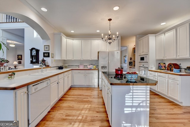 kitchen featuring white appliances, white cabinetry, a sink, and light wood finished floors