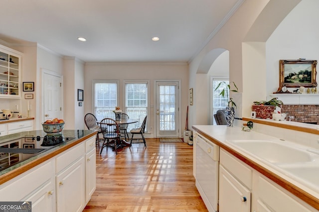 kitchen with arched walkways, crown molding, light wood-style flooring, white cabinetry, and dishwasher