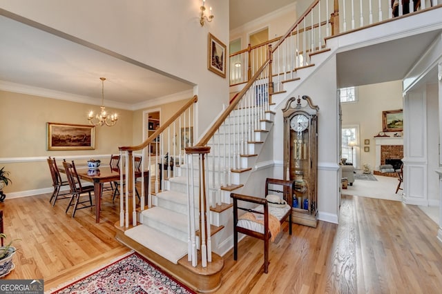 foyer with crown molding, a high ceiling, a fireplace, and wood finished floors