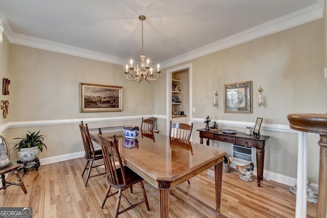 dining room with ornamental molding, a chandelier, light wood-style flooring, and baseboards