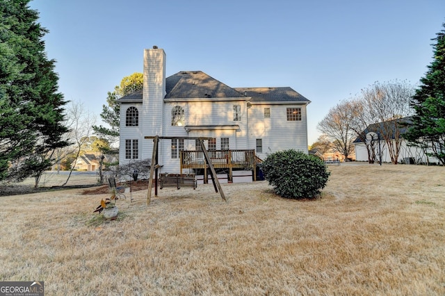 rear view of property with a deck, a chimney, and a lawn