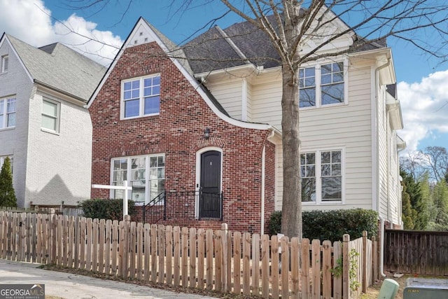 view of front of house featuring brick siding, a fenced front yard, and a shingled roof