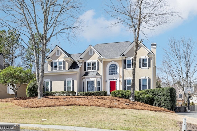 view of front of home featuring a front yard, a chimney, and stucco siding