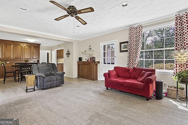 living area featuring light carpet, light tile patterned floors, ceiling fan, and ornamental molding