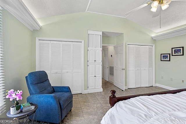 bedroom featuring multiple closets, visible vents, vaulted ceiling, and a textured ceiling