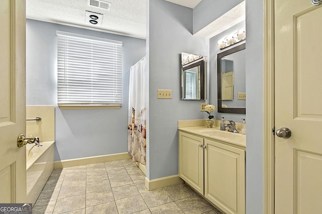 bathroom with baseboards, visible vents, a textured ceiling, vanity, and a bath