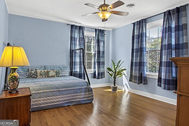 bedroom with visible vents, ceiling fan, baseboards, and wood finished floors