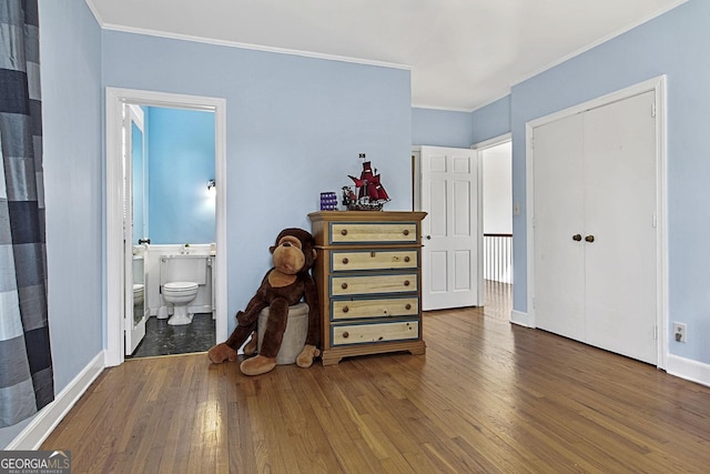 bedroom with hardwood / wood-style flooring, baseboards, ornamental molding, and a closet