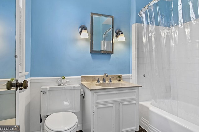 bathroom featuring toilet, a wainscoted wall, shower / bathtub combination with curtain, and vanity