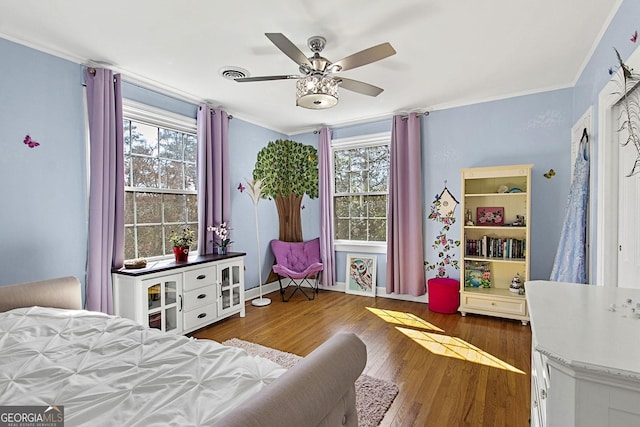 bedroom with multiple windows, wood finished floors, visible vents, and crown molding