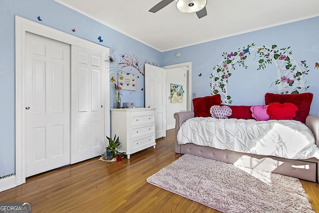 bedroom with a closet, wood finished floors, a ceiling fan, and crown molding