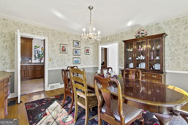 dining area with a notable chandelier, visible vents, ornamental molding, hardwood / wood-style floors, and wallpapered walls