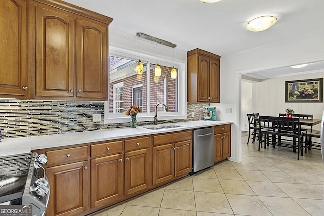 kitchen with light tile patterned floors, stainless steel appliances, a sink, light countertops, and brown cabinets