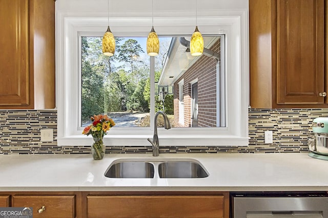 kitchen with decorative backsplash, brown cabinets, decorative light fixtures, light countertops, and a sink