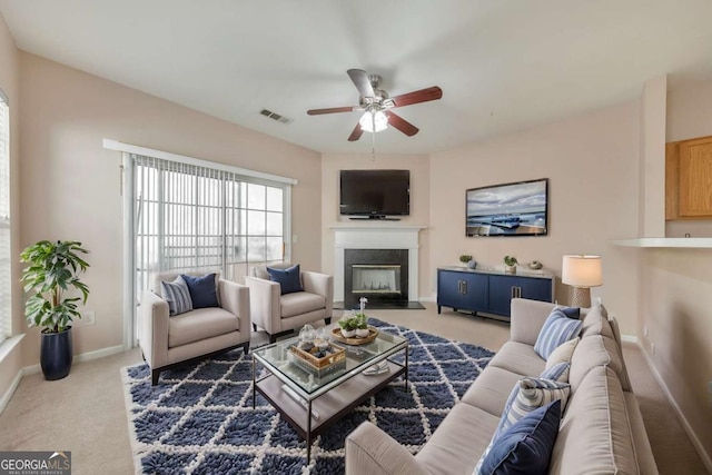 living area featuring visible vents, a fireplace with flush hearth, carpet, baseboards, and ceiling fan