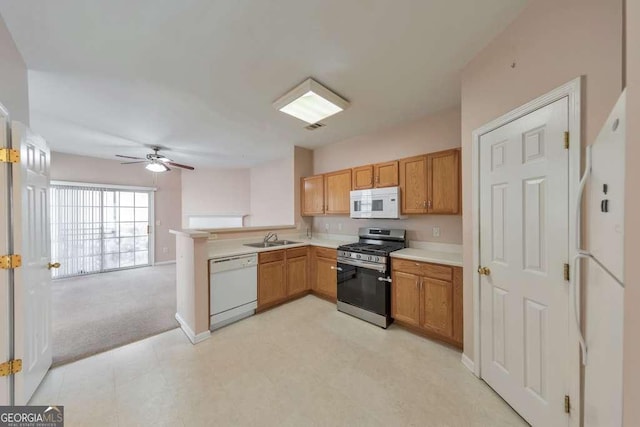 kitchen featuring visible vents, light countertops, a peninsula, white appliances, and a sink