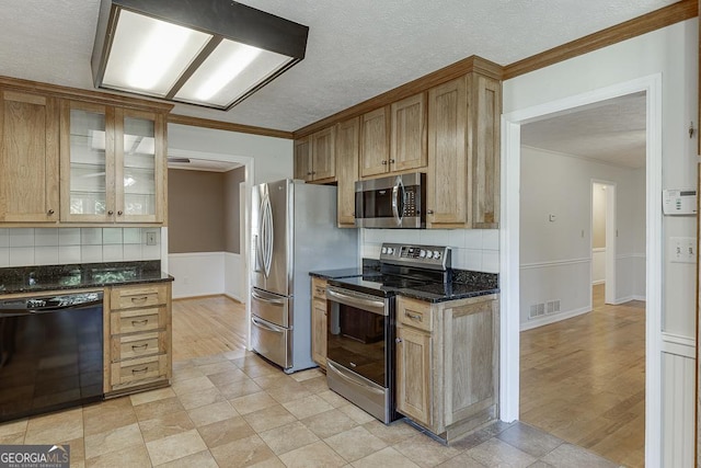 kitchen featuring stainless steel appliances, a textured ceiling, backsplash, dark stone countertops, and ornamental molding