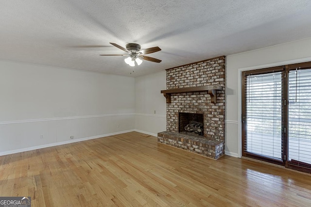 unfurnished living room featuring a ceiling fan, light wood finished floors, a textured ceiling, a fireplace, and baseboards