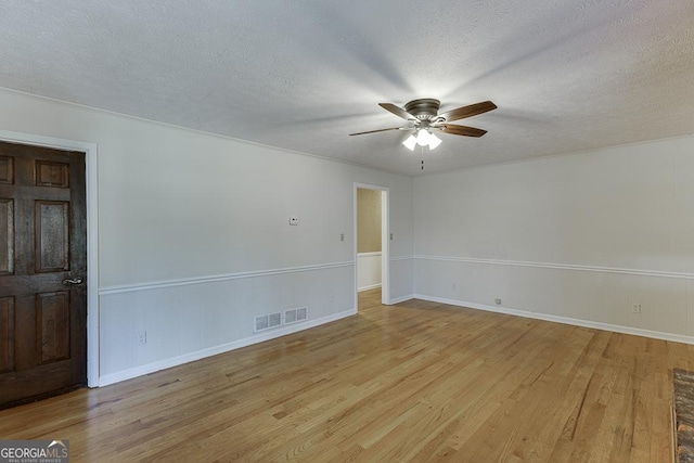 spare room featuring a ceiling fan, light wood finished floors, a textured ceiling, and baseboards